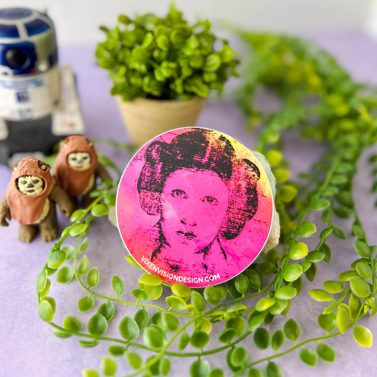 Rebel Resonance 3" Circle Sticker against a rock and greenery