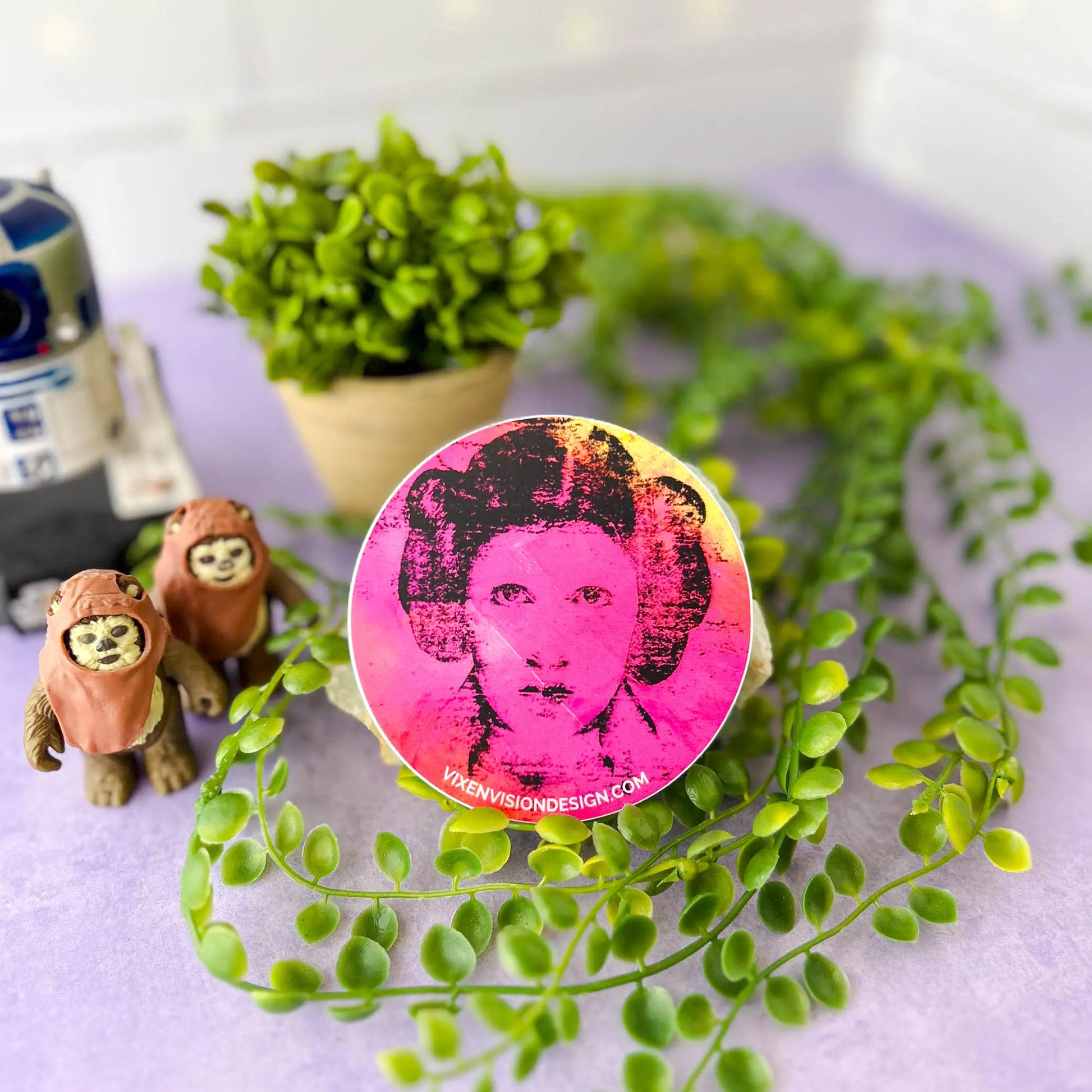 Rebel Resonance 3" Circle Sticker against a rock and greenery with Ewoks