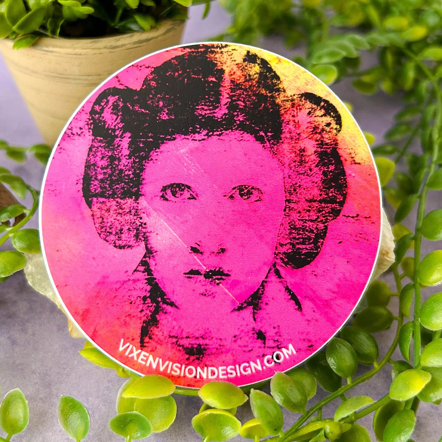 Rebel Resonance 3" Circle Sticker against a rock and greenery