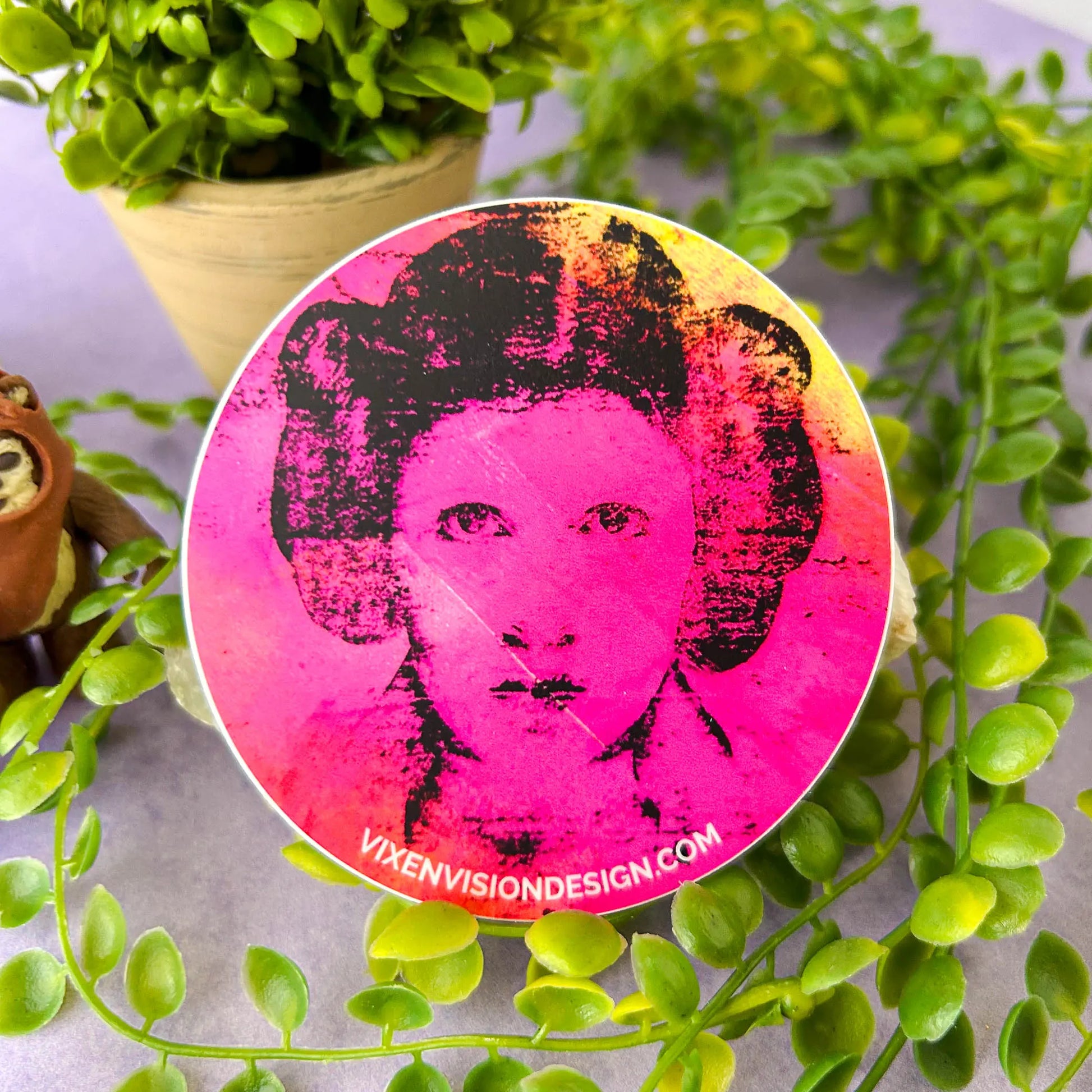 Rebel Resonance 3" Circle Sticker against a rock and greenery with an Ewok