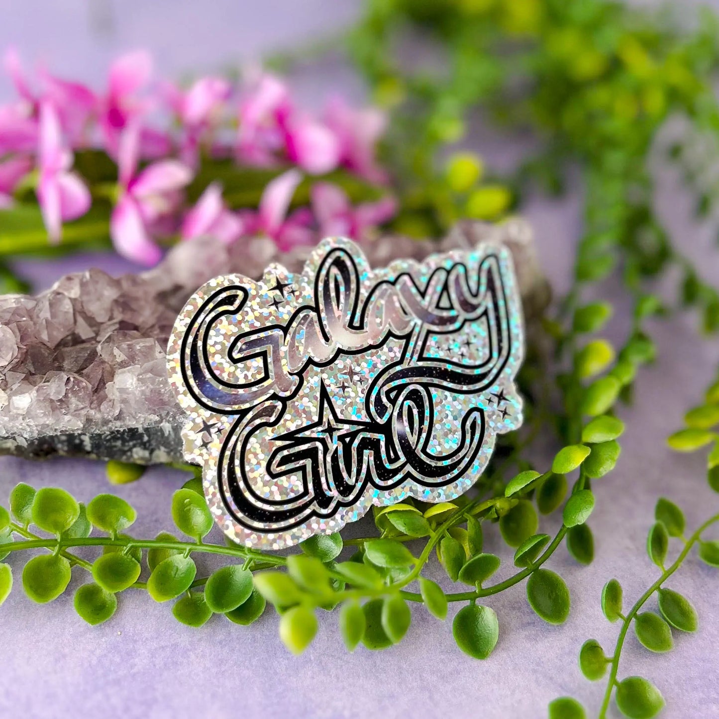 Galaxy Girl Die-Cut Sparkle 3" Vinyl Sticker against amethyst rock with greenery