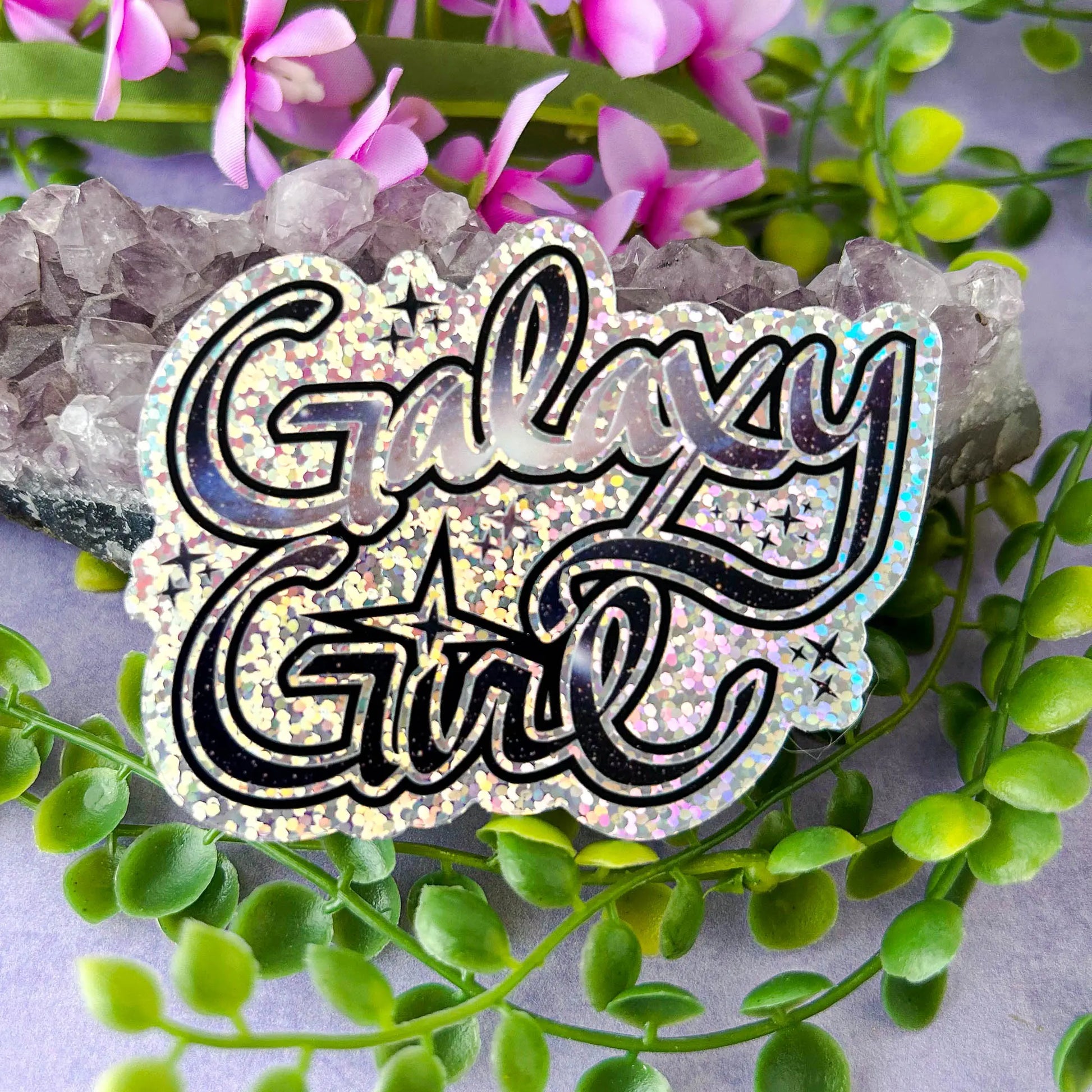 Galaxy Girl Die-Cut Sparkle 3" Vinyl Sticker against amethyst rock with greenery