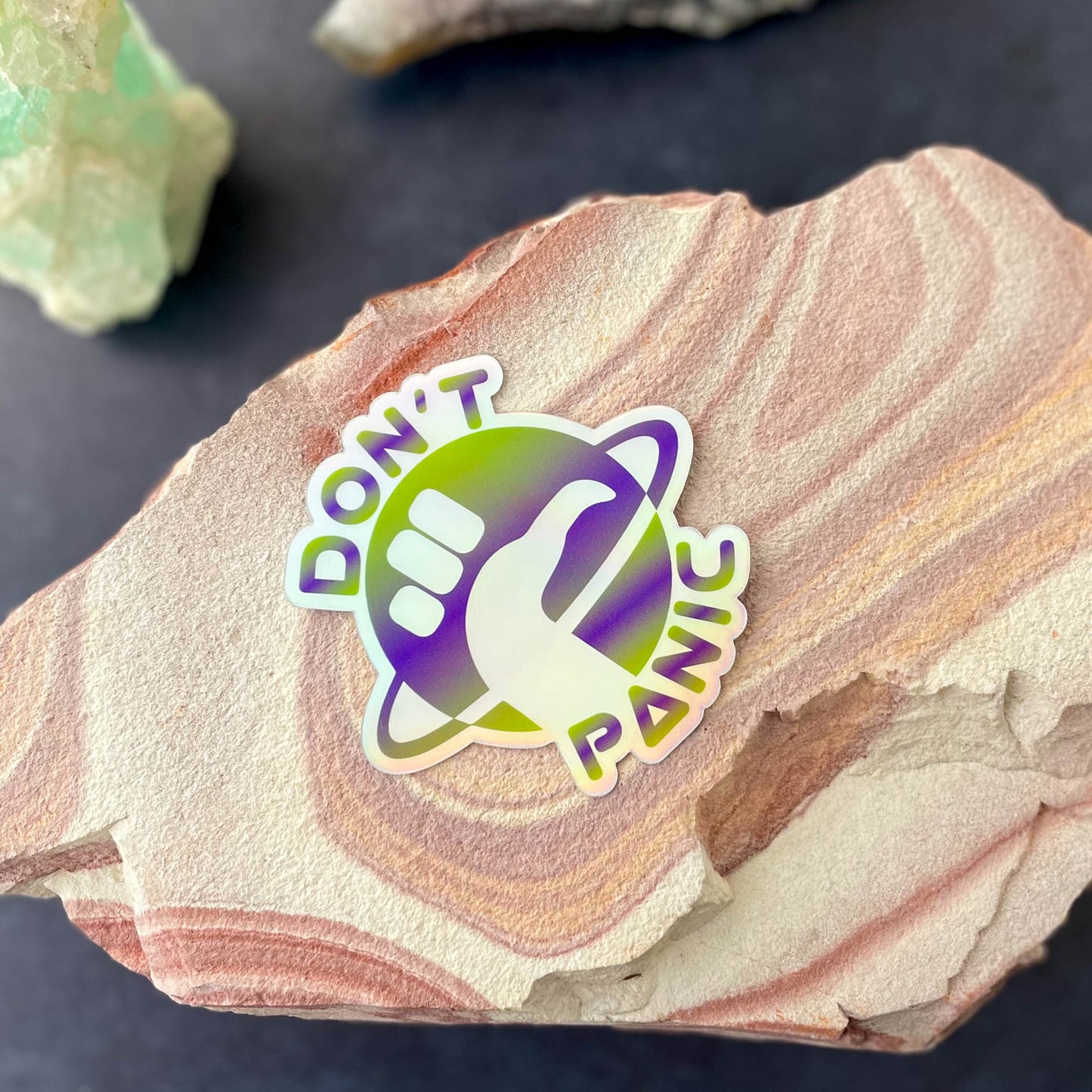 Don't Panic Holographic 3" Sticker on rock