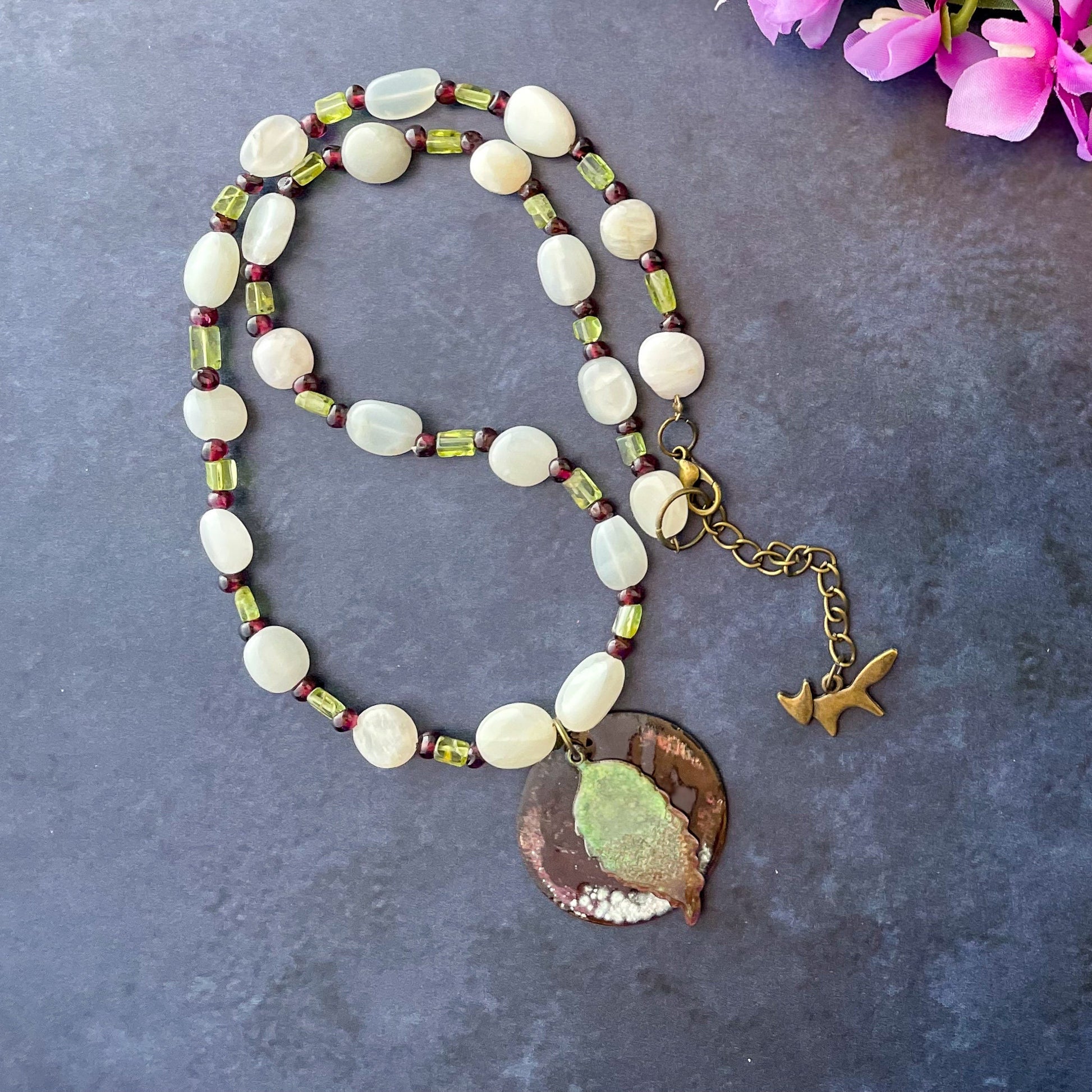 Green Leaf and Burgundy Circle Layered Enamel Pendant Moonstone, Garnet, and Peridot Bead Necklace on slate