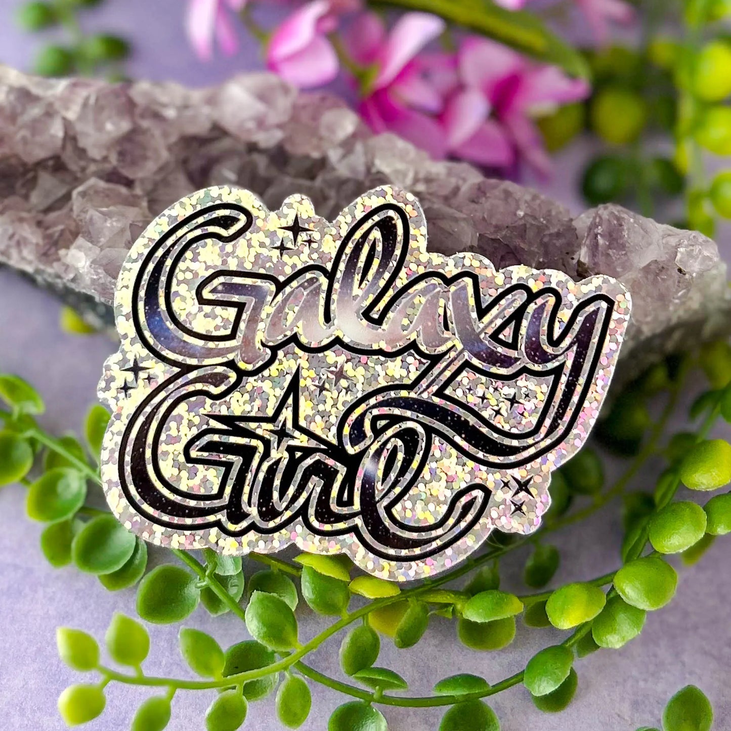 Galaxy Girl Die-Cut Sparkle 3" Vinyl Sticker against amethyst rock with greenery