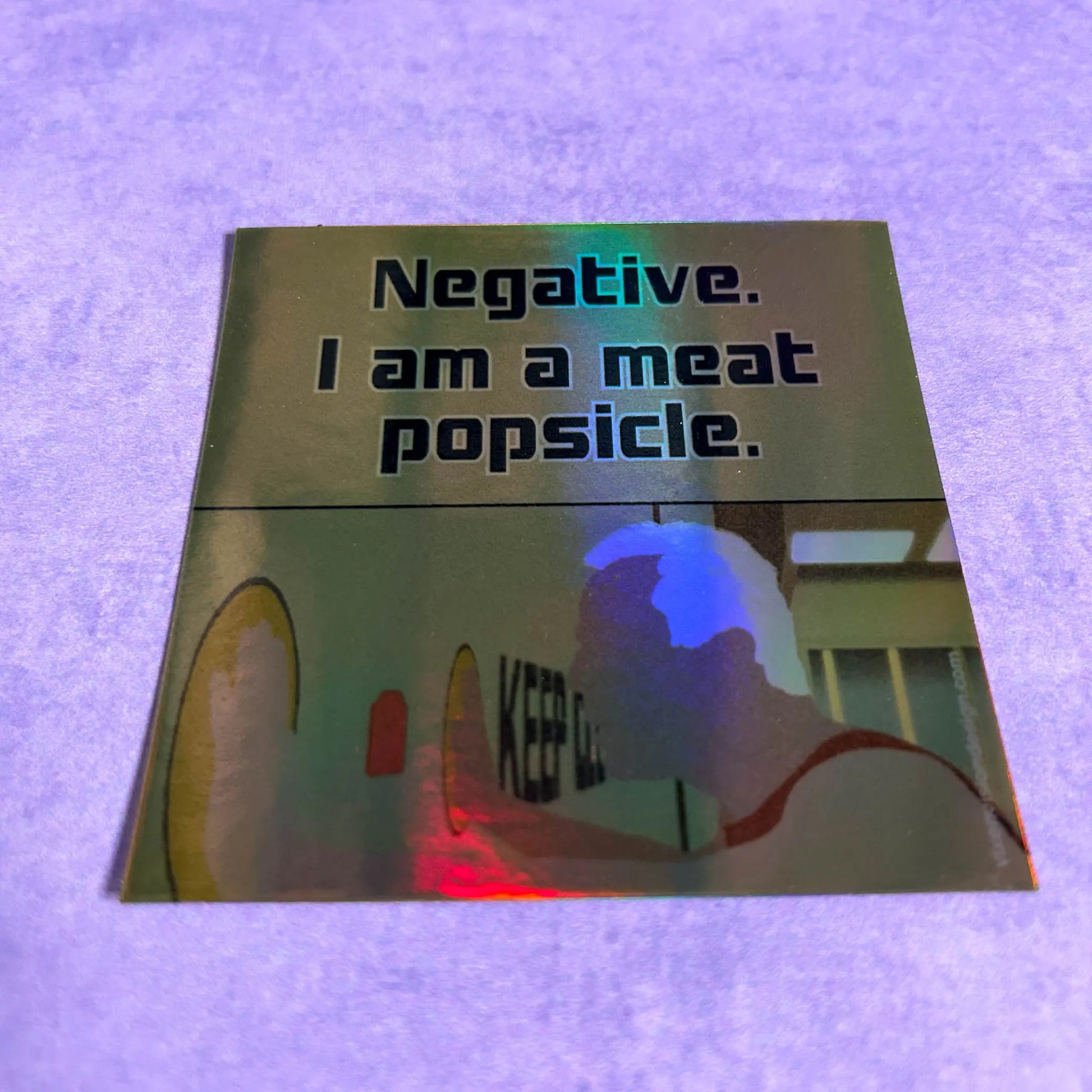 Meat Popsicle Holographic 3" Vinyl Sticker tilted back on a purple background