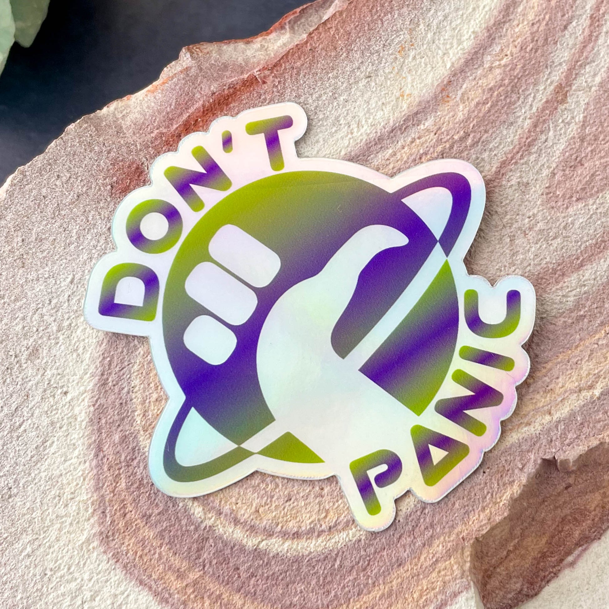 Don't Panic Holographic 3" Sticker on rock