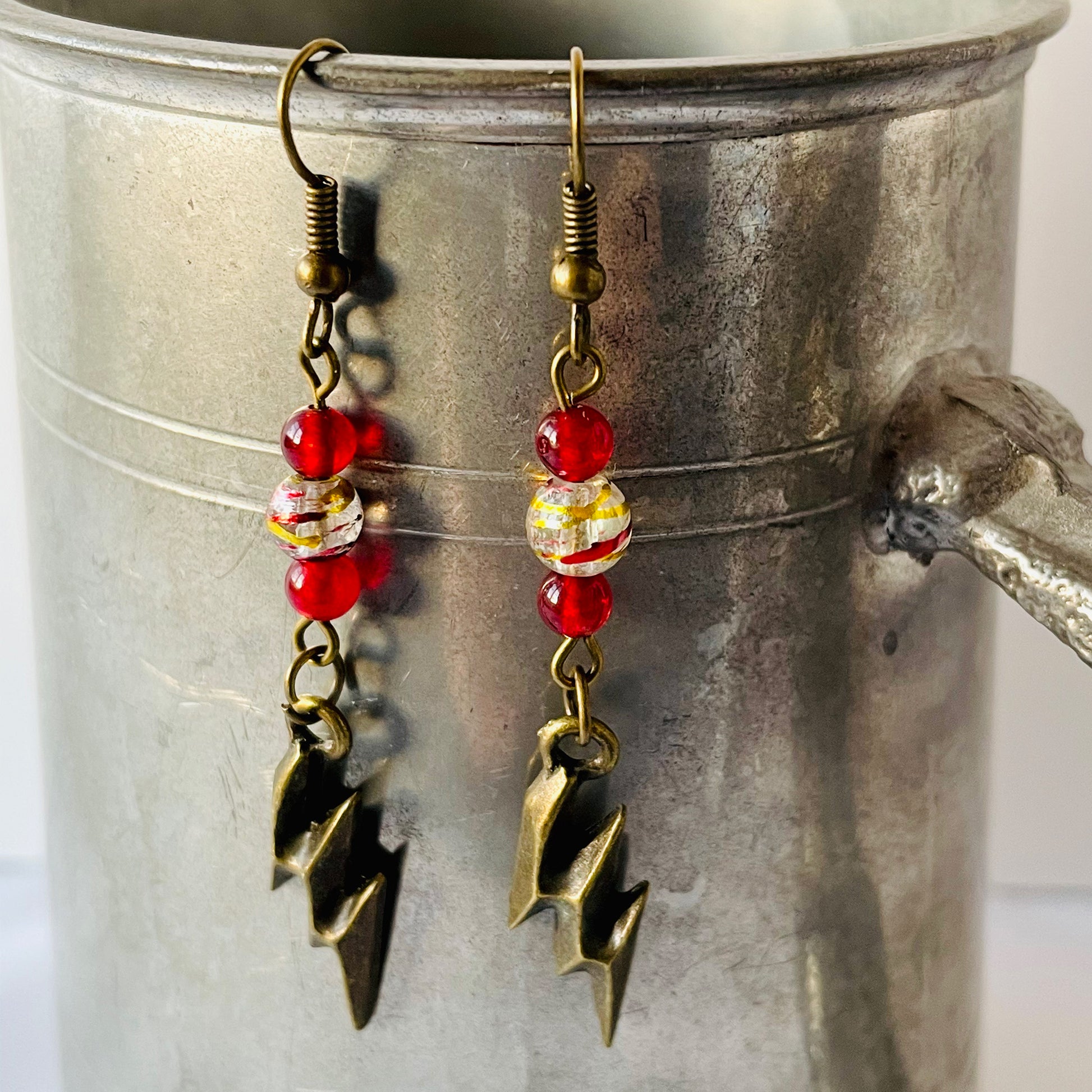 Antique Bronze and Glass Bead Lightning Bolt Earrings on pewter mug