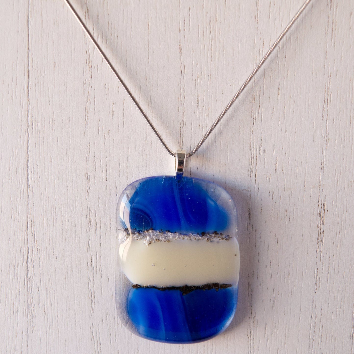 Cobalt Blue and Cream Abstract Fused Glass Pendant Necklace on white wood