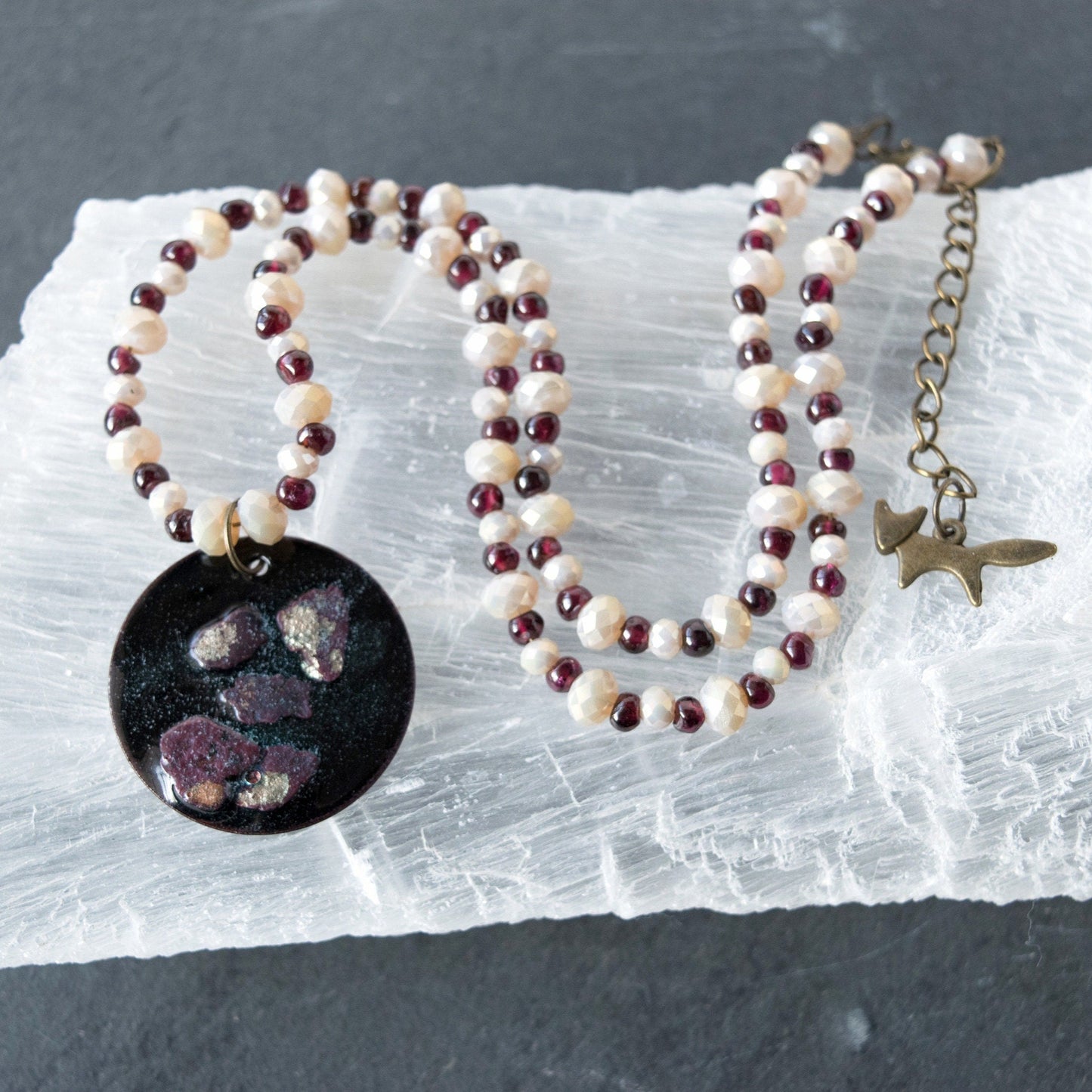 Copper Enamel Pendant and Garnet and Glass Bead Necklace on selenite