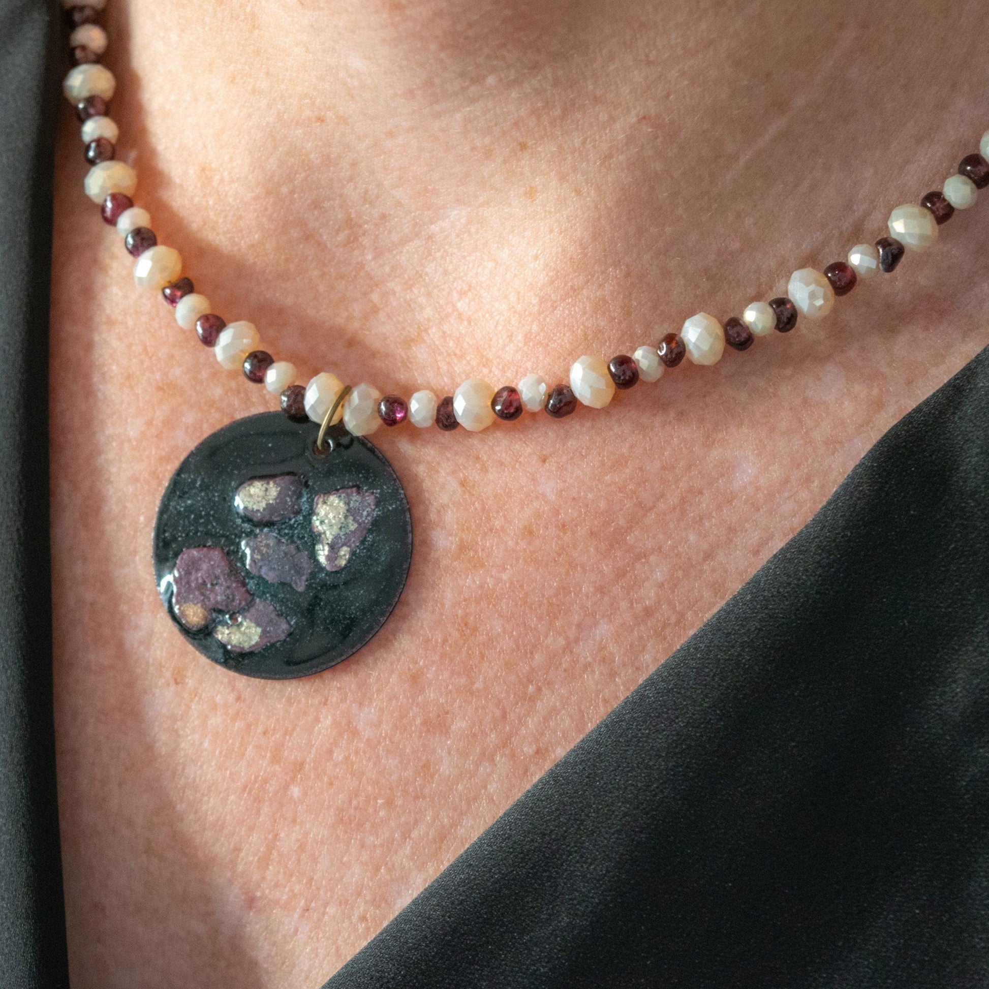 Copper Enamel Pendant and Garnet and Glass Bead Necklace on model to the left